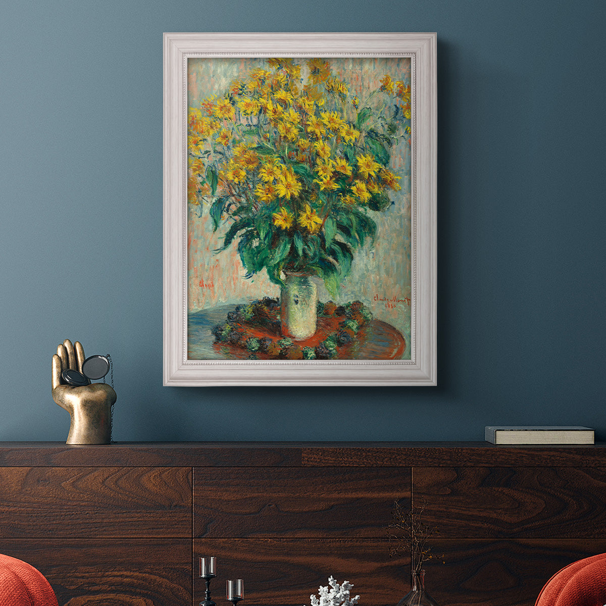 Impressionist floral painting of artichoke flowers by Claude Monet in an ornate weathered white frame displayed in a dark-toned interior setting.