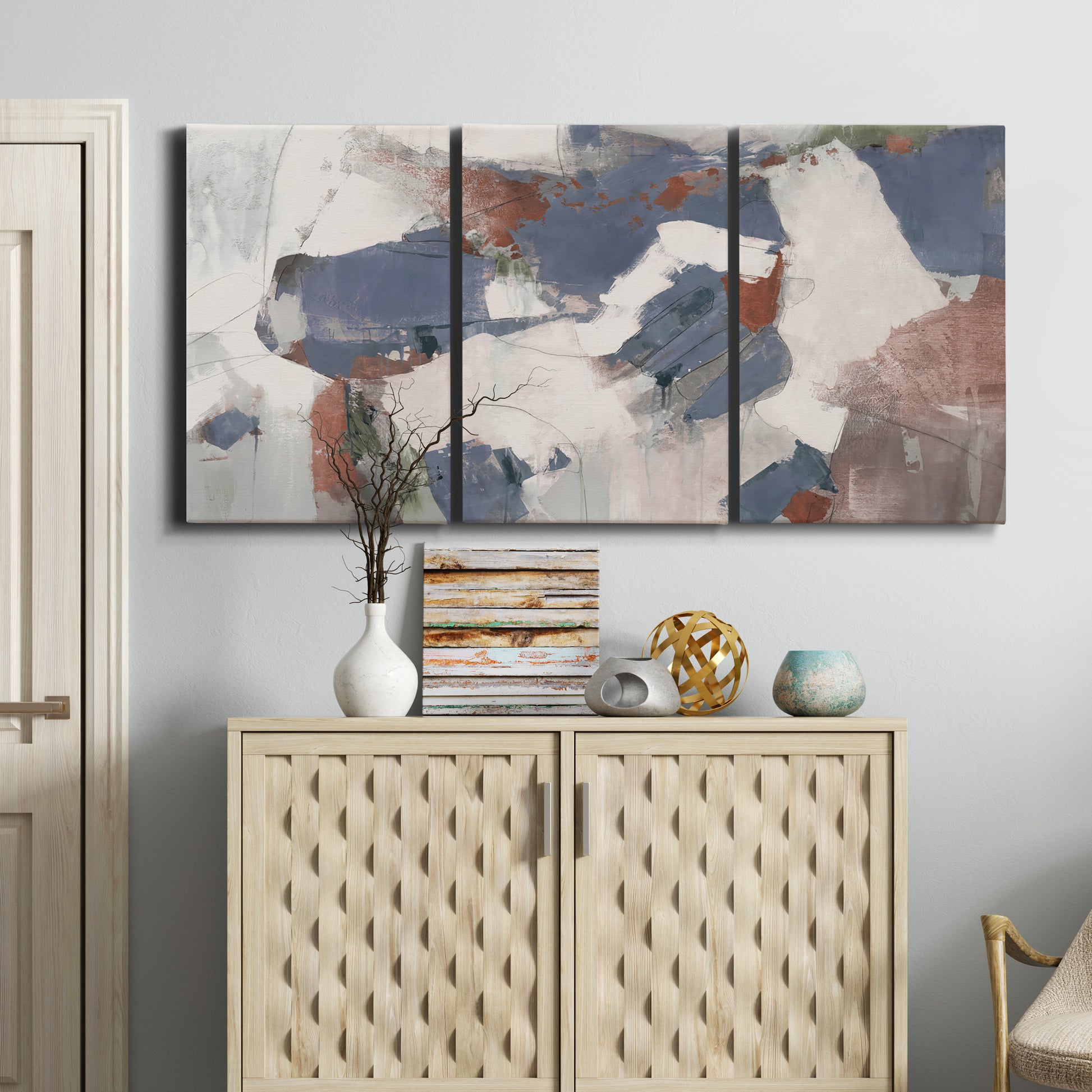 Three-panel canvas wall art featuring cool blue abstract layered composition, displayed above a cabinet in an entryway.