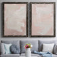 Set of two black barnwood framed canvas prints depicting paired minimalist color-field abstracts with cloudy rose washes, broad pale strokes, and subtle texture above a sofa in a contemporary living room.