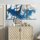 Three-panel canvas wall art featuring flowing blue abstract movement, displayed above a cabinet in an entryway.