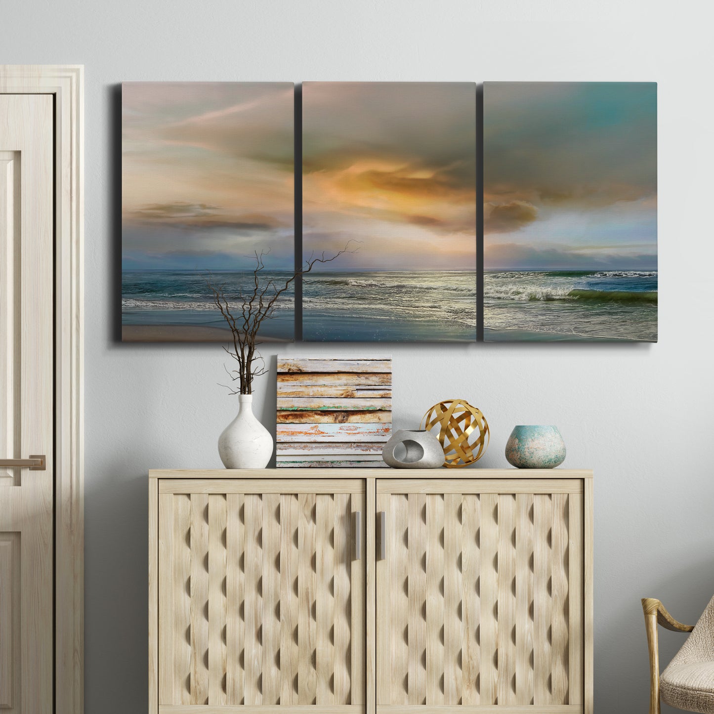 Three-panel canvas wall art featuring tranquil beach at sunset, displayed above a cabinet in an entryway.