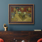 Impressionist interior of a night café by Vincent van Gogh in an ornate bronzed mahogany wood frame displayed in a dark-toned interior setting.