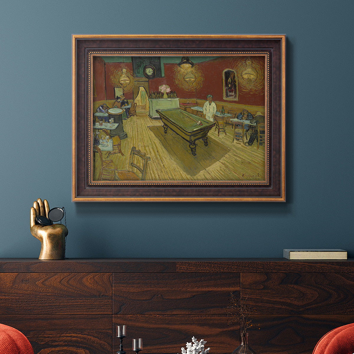 Impressionist interior of a night café by Vincent van Gogh in an ornate bronzed mahogany wood frame displayed in a dark-toned interior setting.