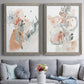 Set of two gray barnwood framed canvas prints depicting paired abstract watercolor botanicals with scribbled petals, translucent washes, and drifting stems above a sofa in a contemporary living room.
