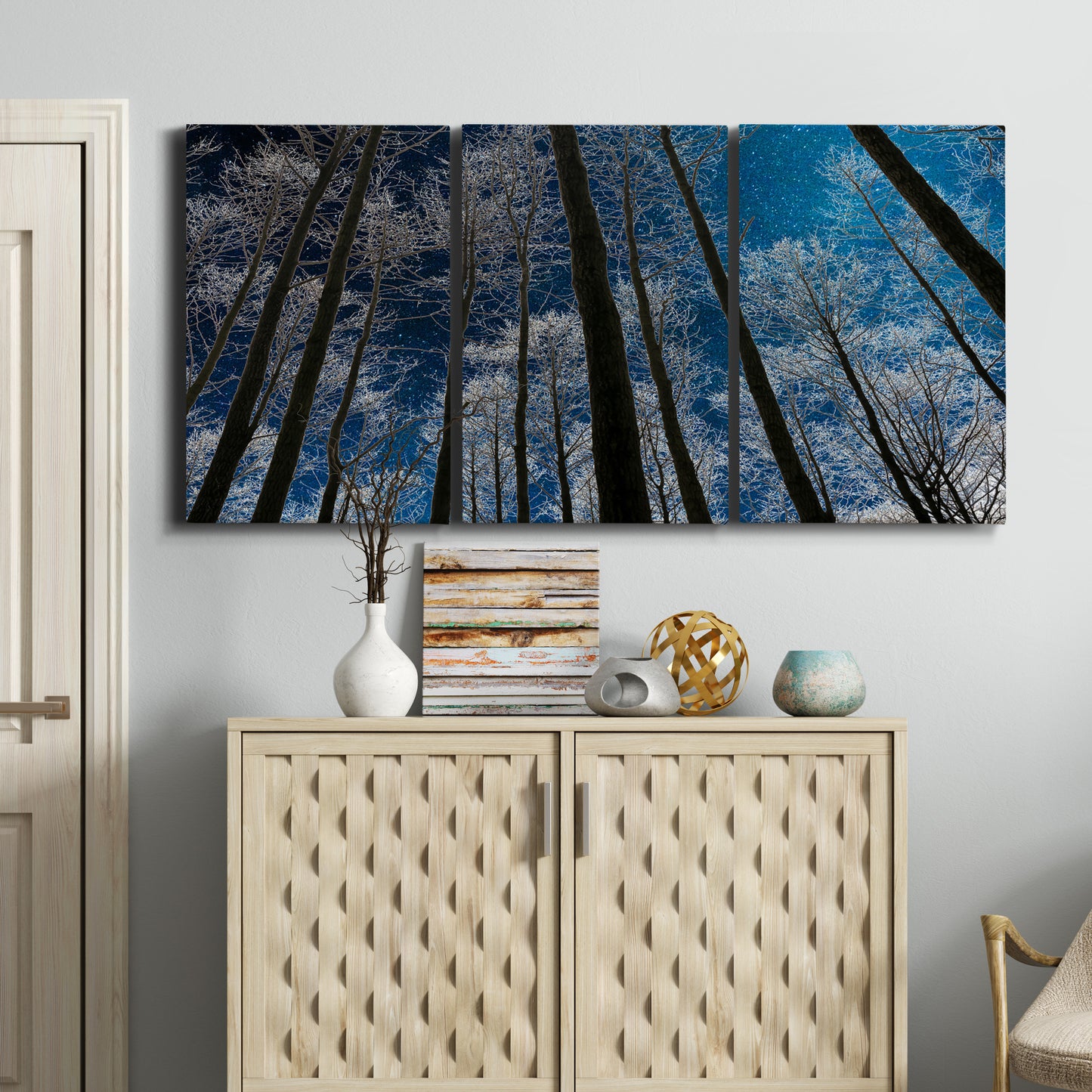 Three-panel canvas wall art featuring night landscape silhouette photography, displayed above a cabinet in an entryway.