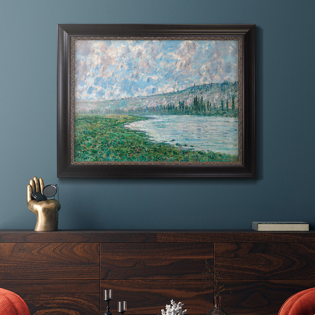 Impressionist river landscape at Vétheuil by Claude Monet in an ornate black frame with gilded inner detail displayed in a dark-toned interior setting.