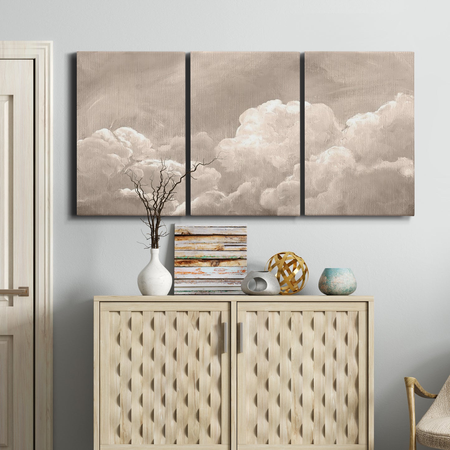 Three-panel canvas wall art featuring soft whimsical cloudscape, displayed above a cabinet in an entryway.