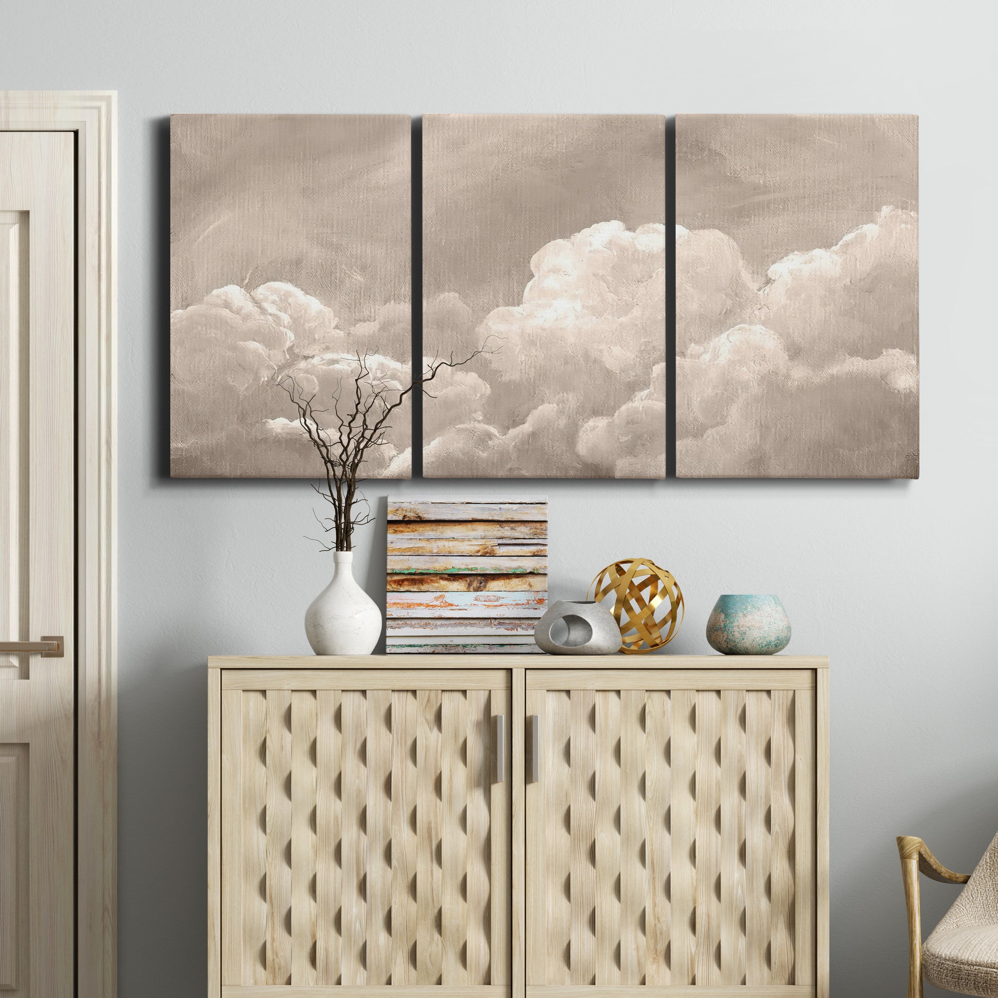 Three-panel canvas wall art featuring soft whimsical cloudscape, displayed above a cabinet in an entryway.