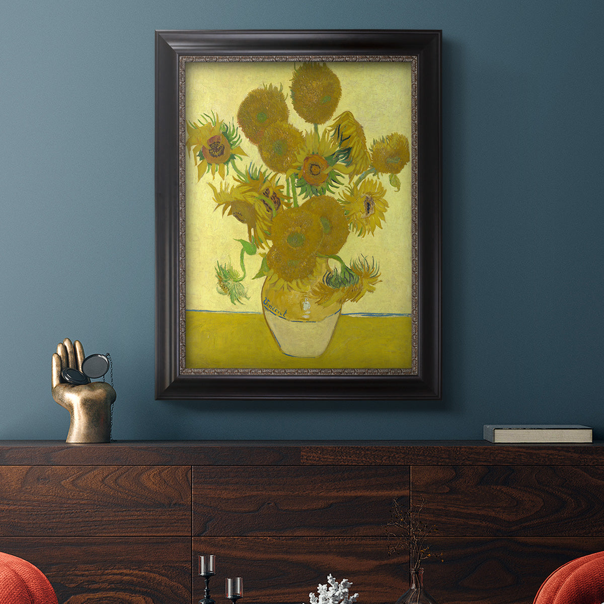 Impressionist sunflower still life painting by Vincent van Gogh in an ornate black frame with gilded inner detail displayed in a dark-toned interior setting.