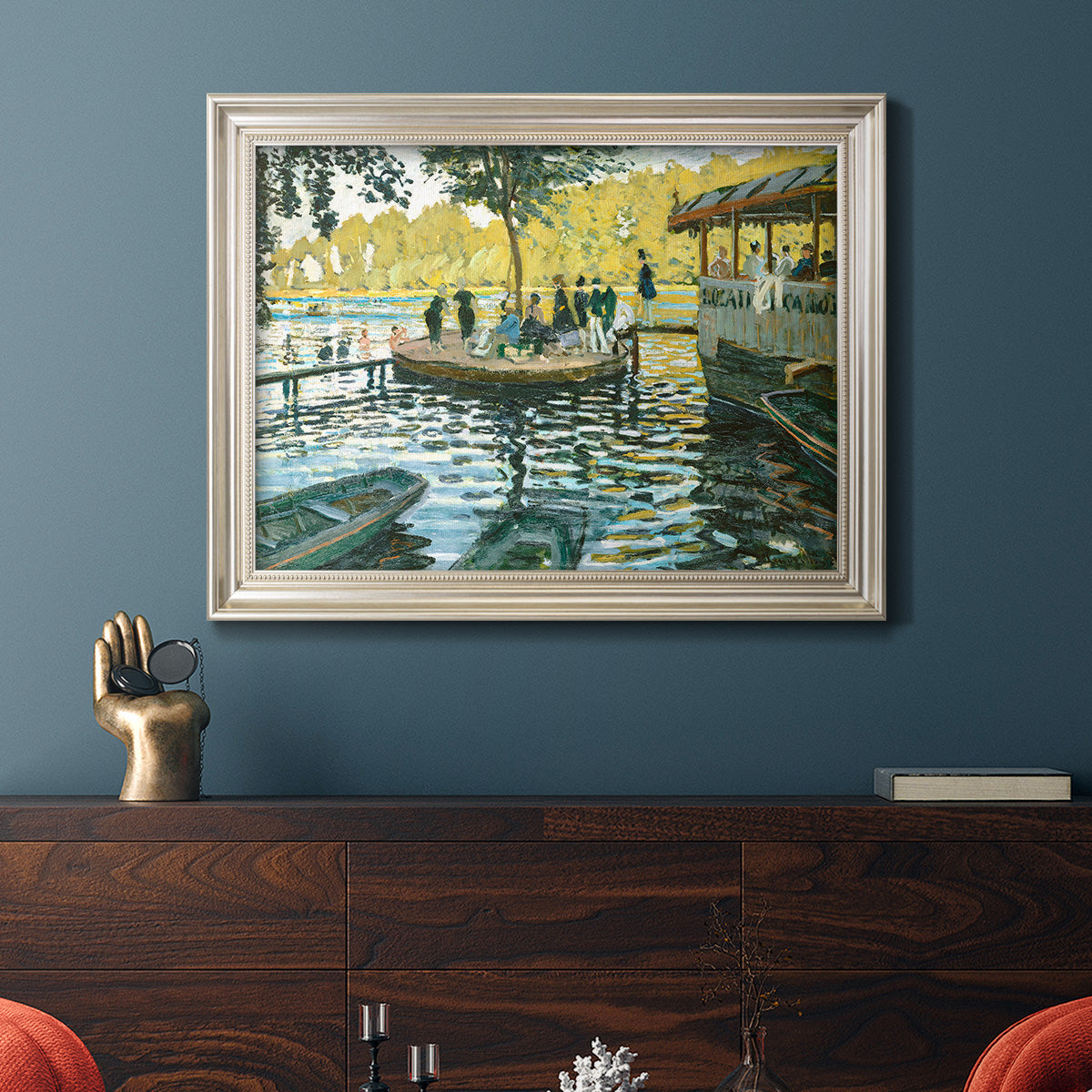 Impressionist riverside leisure scene by Claude Monet in an ornate champagne frame displayed in a dark-toned interior setting.