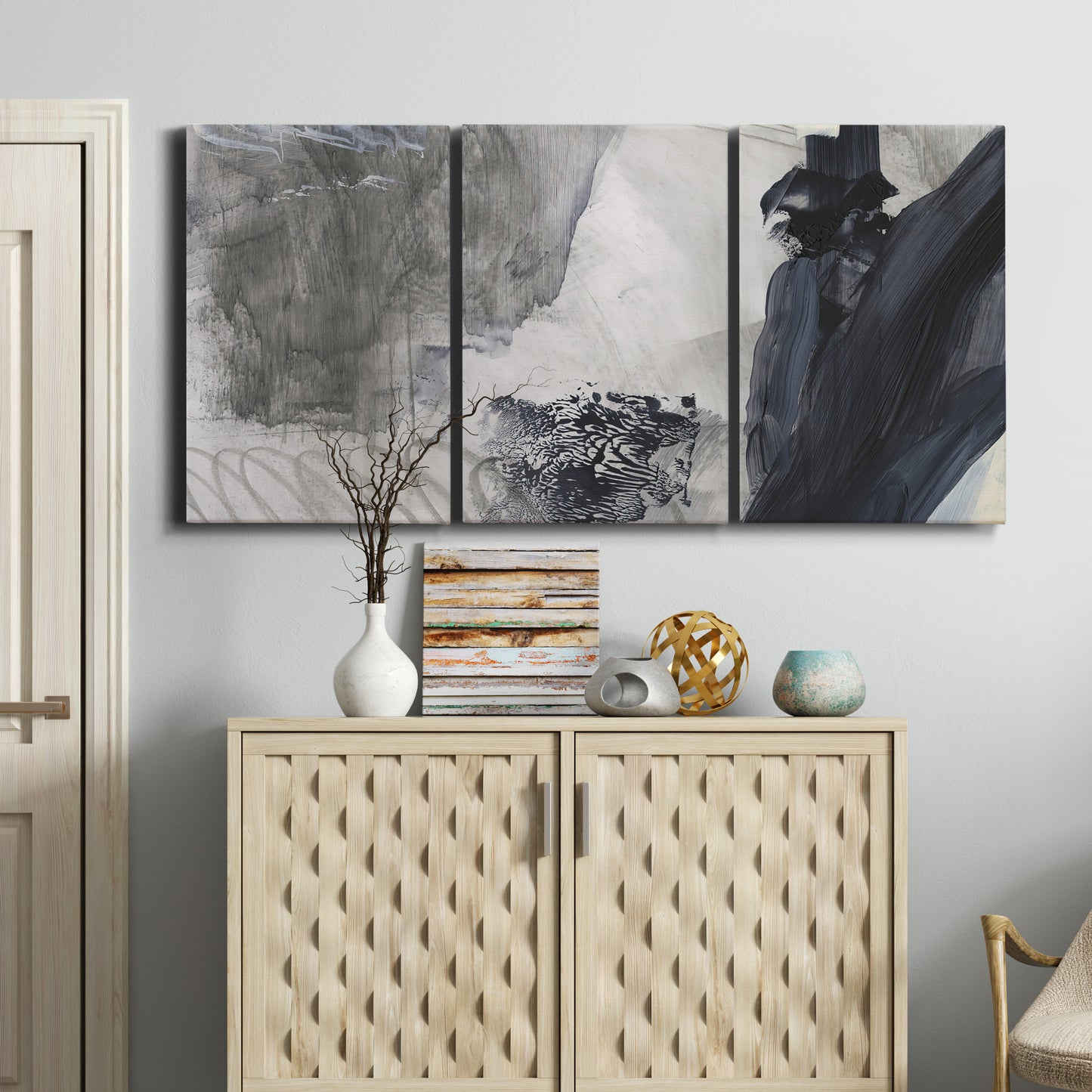Three-panel canvas wall art featuring dark abstract atmospheric landscape, displayed above a cabinet in an entryway.