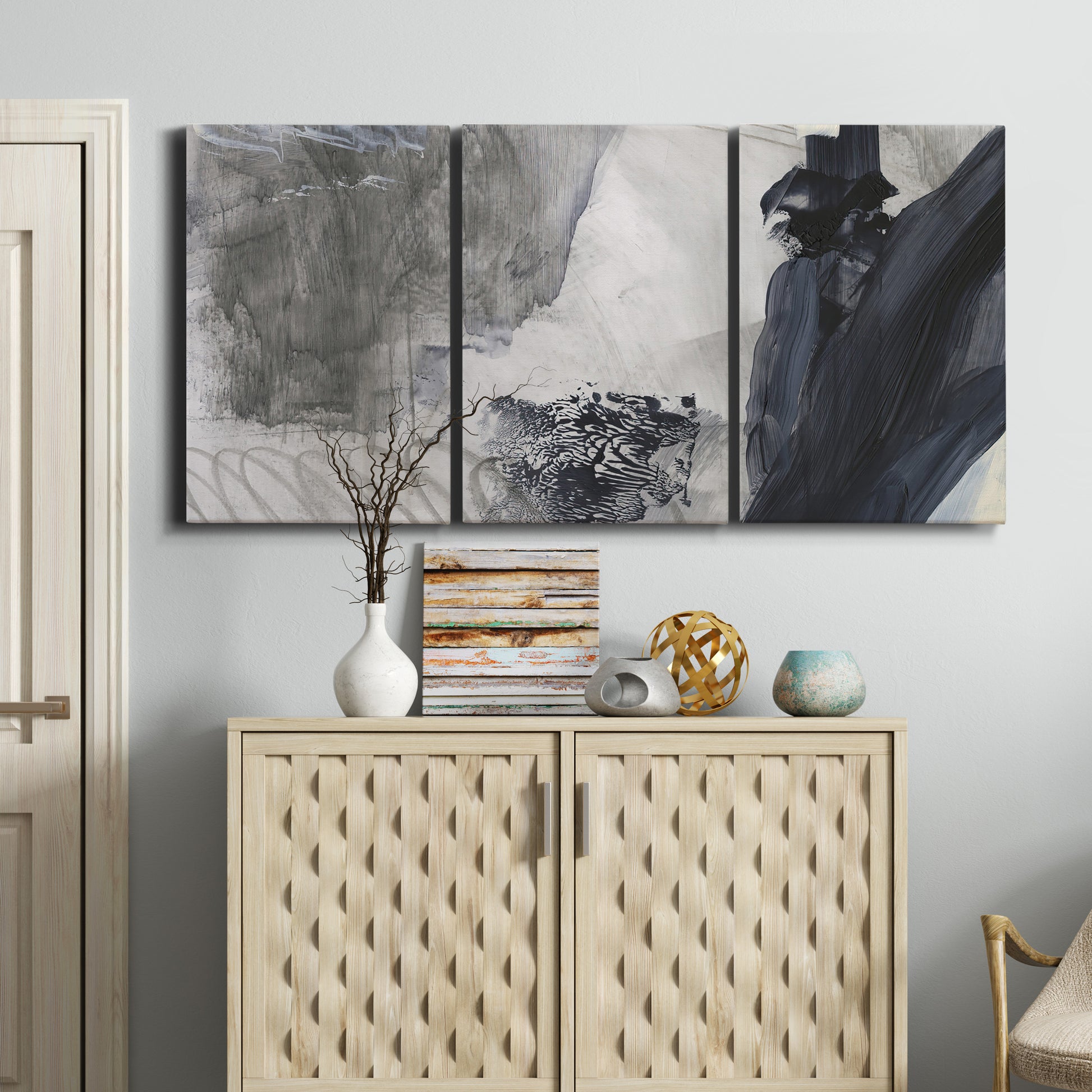 Three-panel canvas wall art featuring dark abstract atmospheric landscape, displayed above a cabinet in an entryway.
