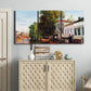 Three-panel canvas wall art featuring riverside houses along canal, displayed above a cabinet in an entryway.