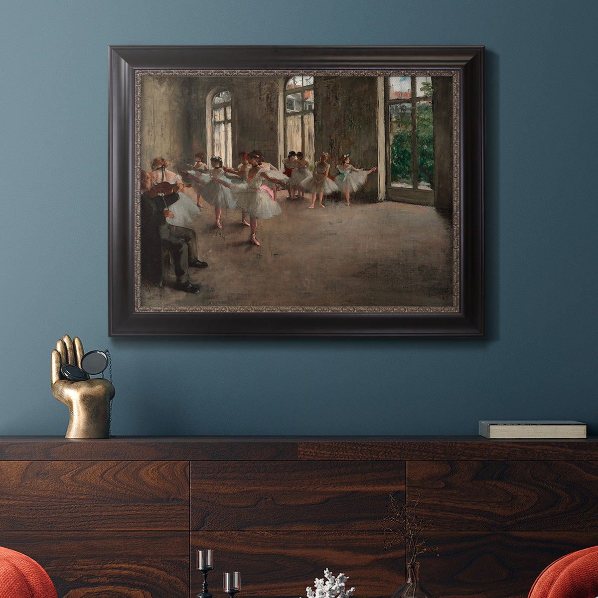 Early impressionist ballet rehearsal painting by Edgar Degas in an ornate black frame with gilded inner detail displayed in a dark-toned interior setting.