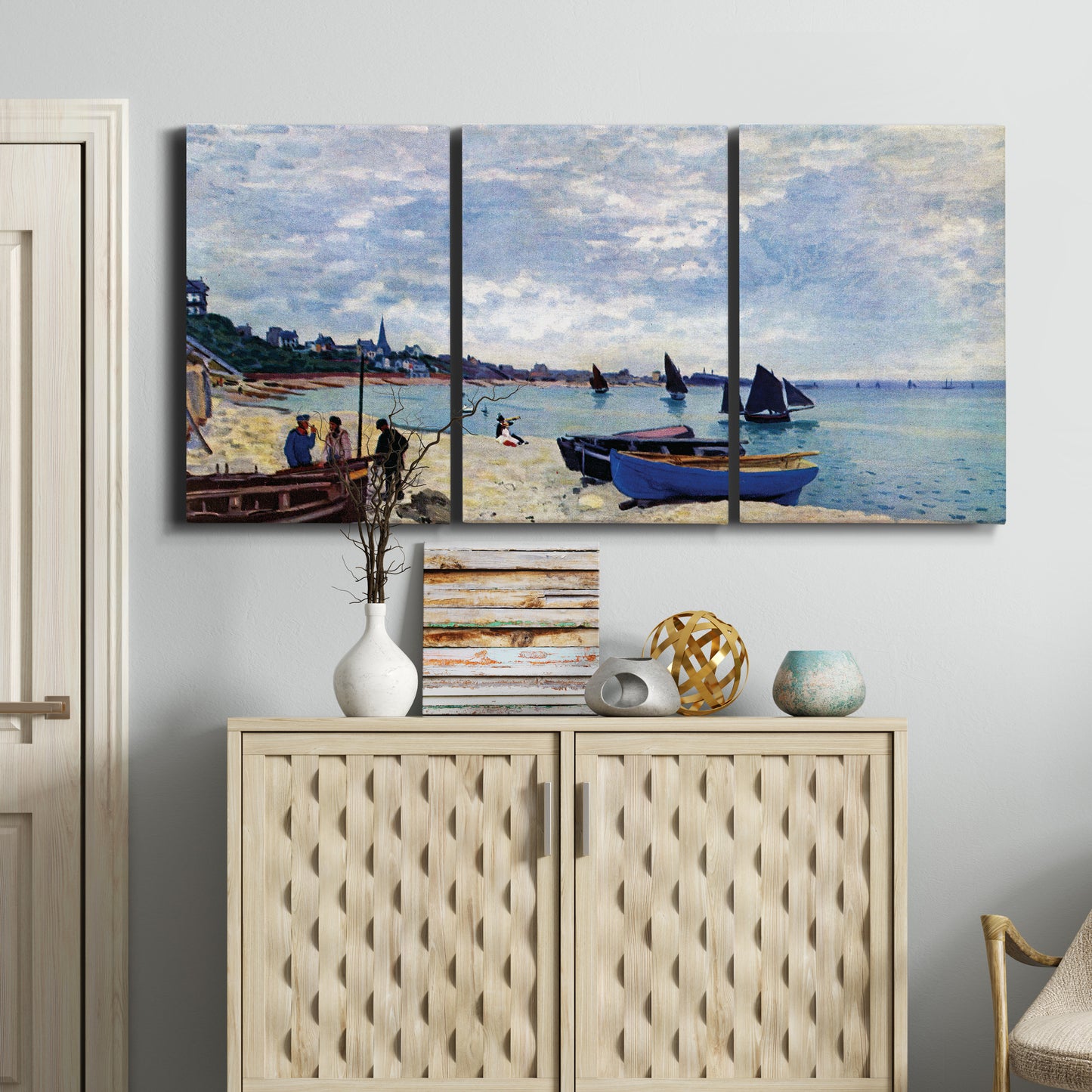 Three-panel canvas wall art featuring busy beach scene with shoreline, displayed above a cabinet in an entryway.