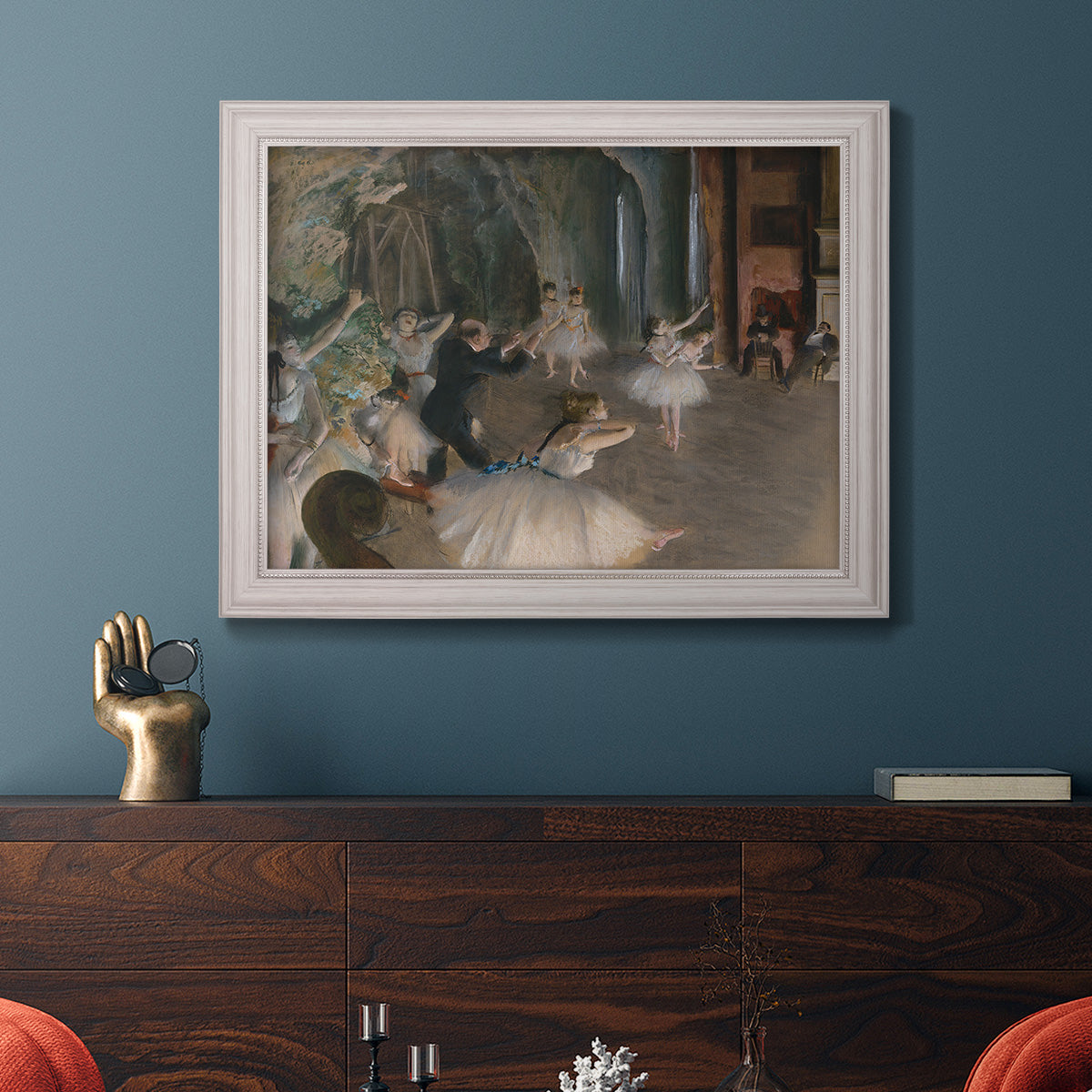 Impressionist backstage ballet scene by Edgar Degas in an ornate weathered white frame displayed in a dark-toned interior setting.