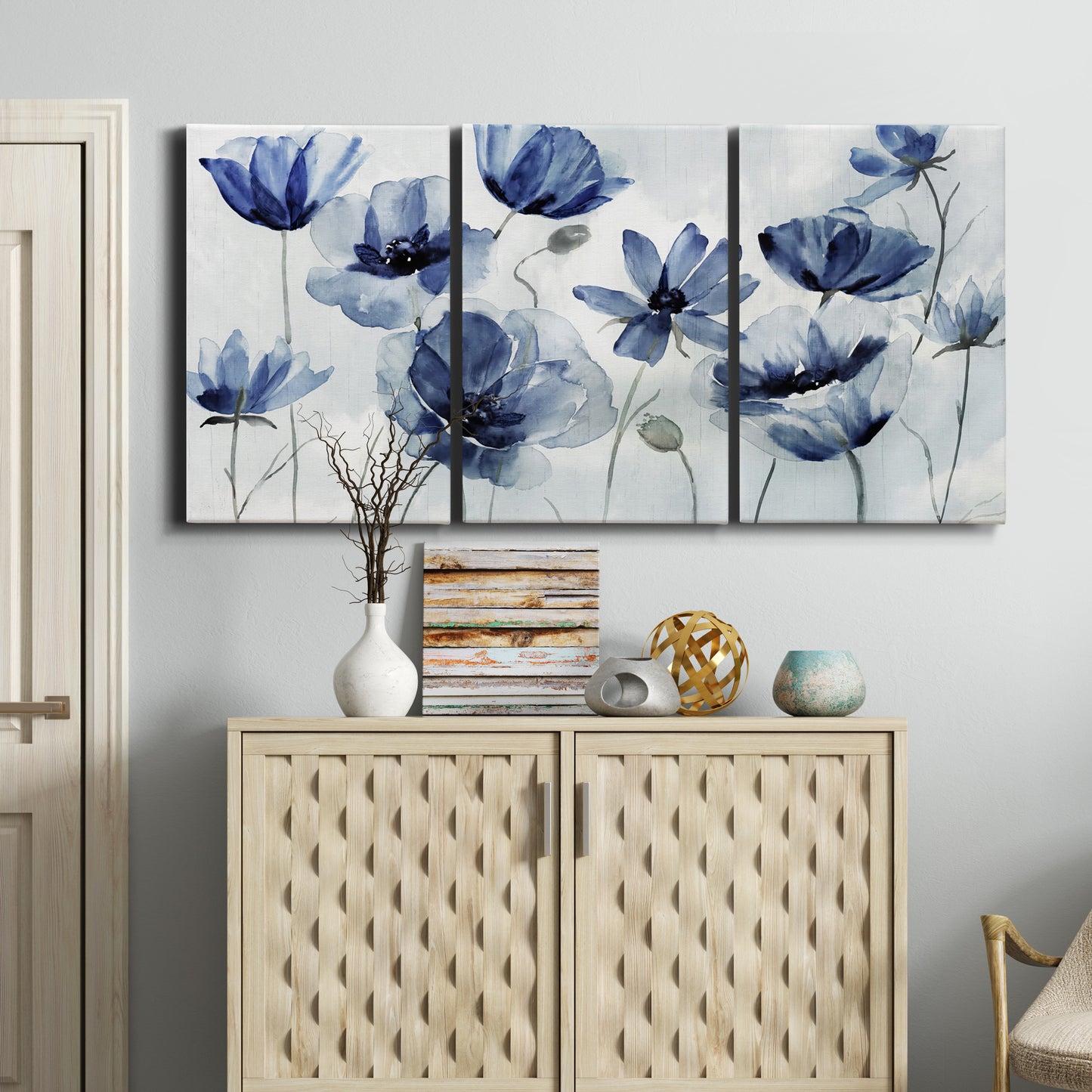 Three-panel canvas wall art featuring indigo floral blossoms awakening, displayed above a cabinet in an entryway.
