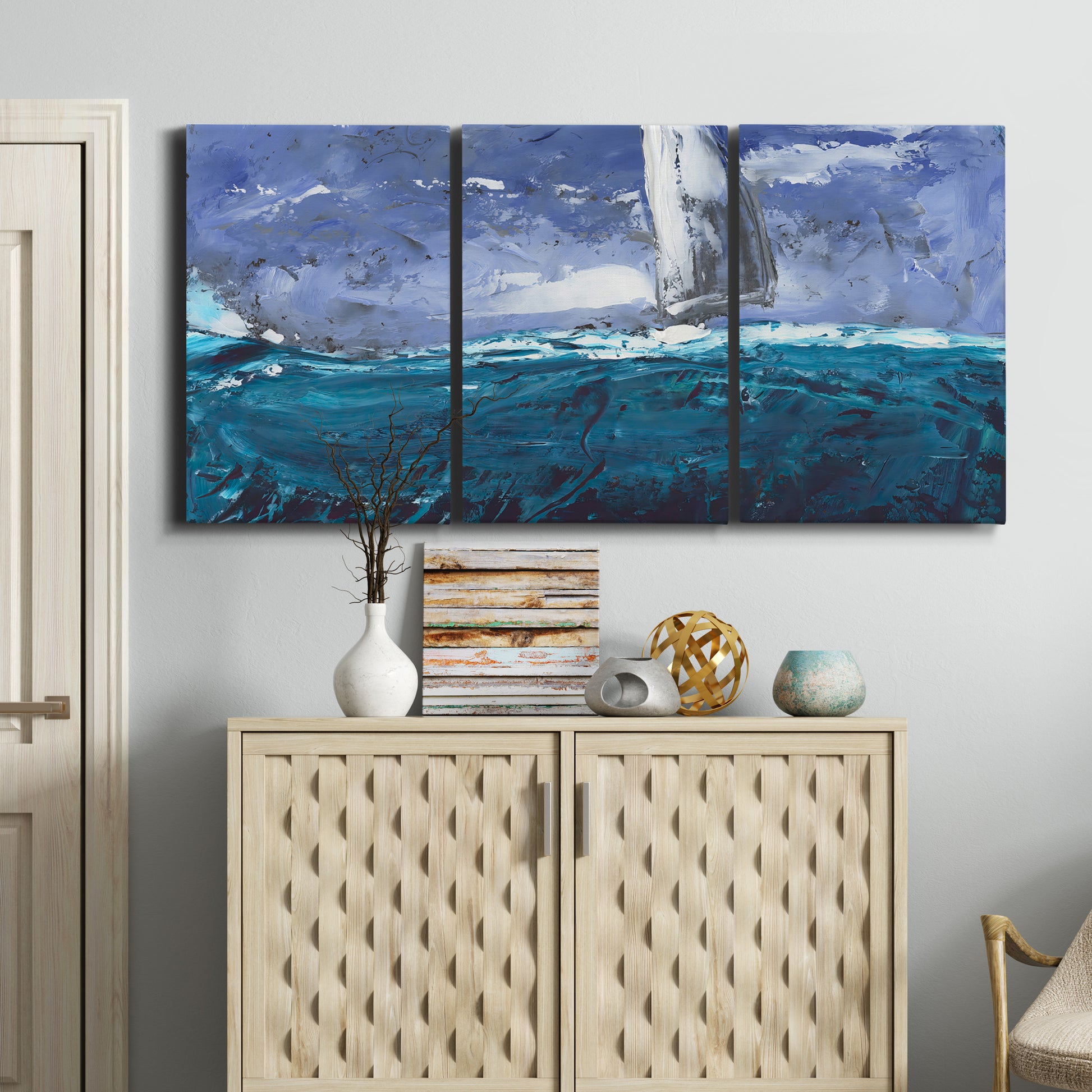 Three-panel canvas wall art featuring sailboats moving across water, displayed above a cabinet in an entryway.