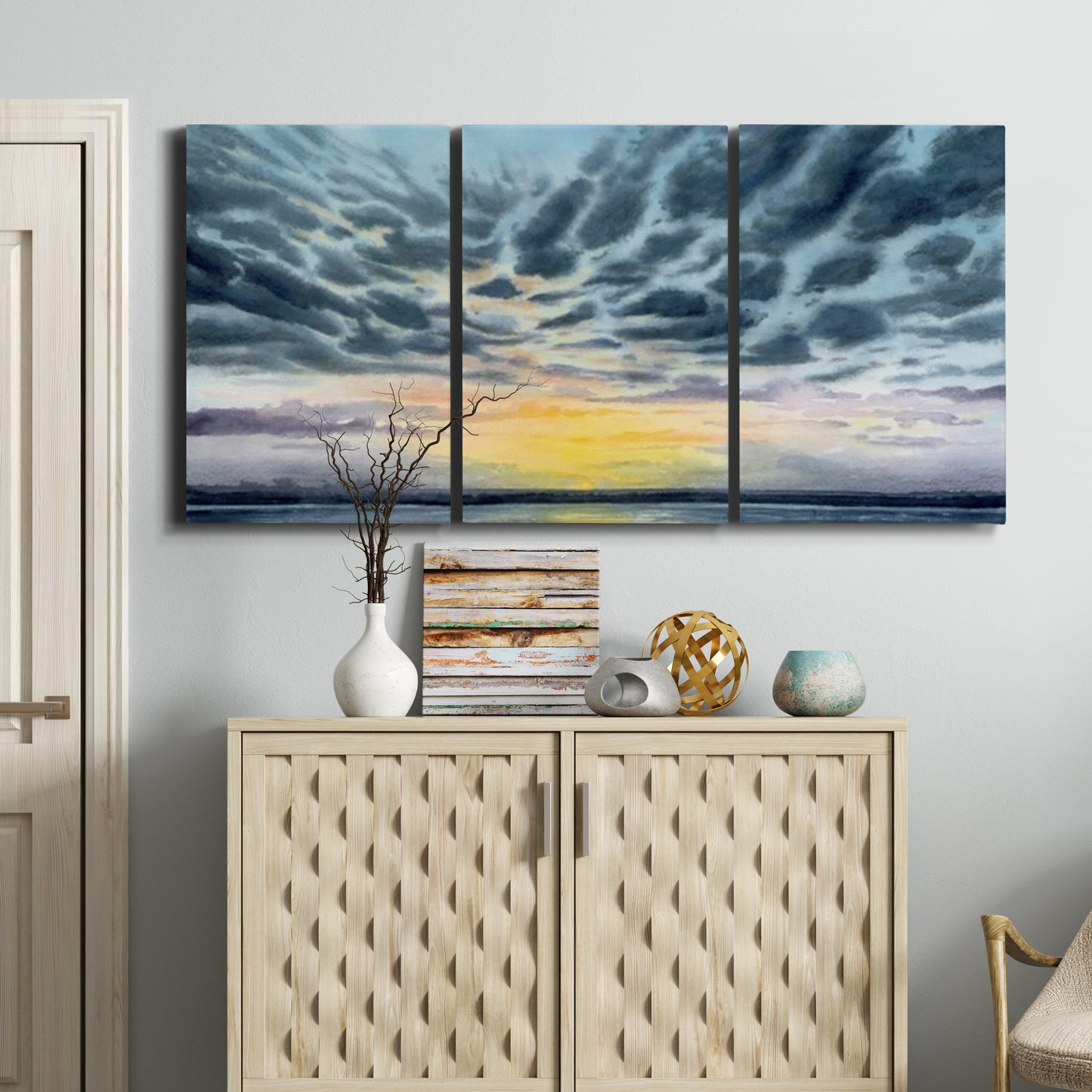 Three-panel canvas wall art featuring tropical coastal sunset over water, displayed above a cabinet in an entryway.