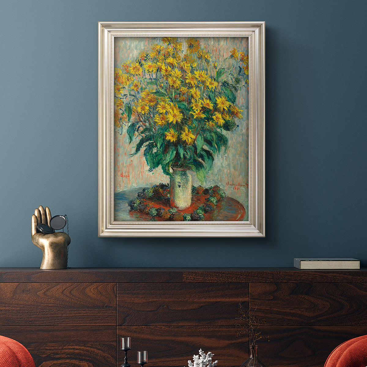 Impressionist floral painting of artichoke flowers by Claude Monet in an ornate champagne frame displayed in a dark-toned interior setting.