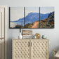 Three-panel canvas wall art featuring winding coastal road above sea, displayed above a cabinet in an entryway.