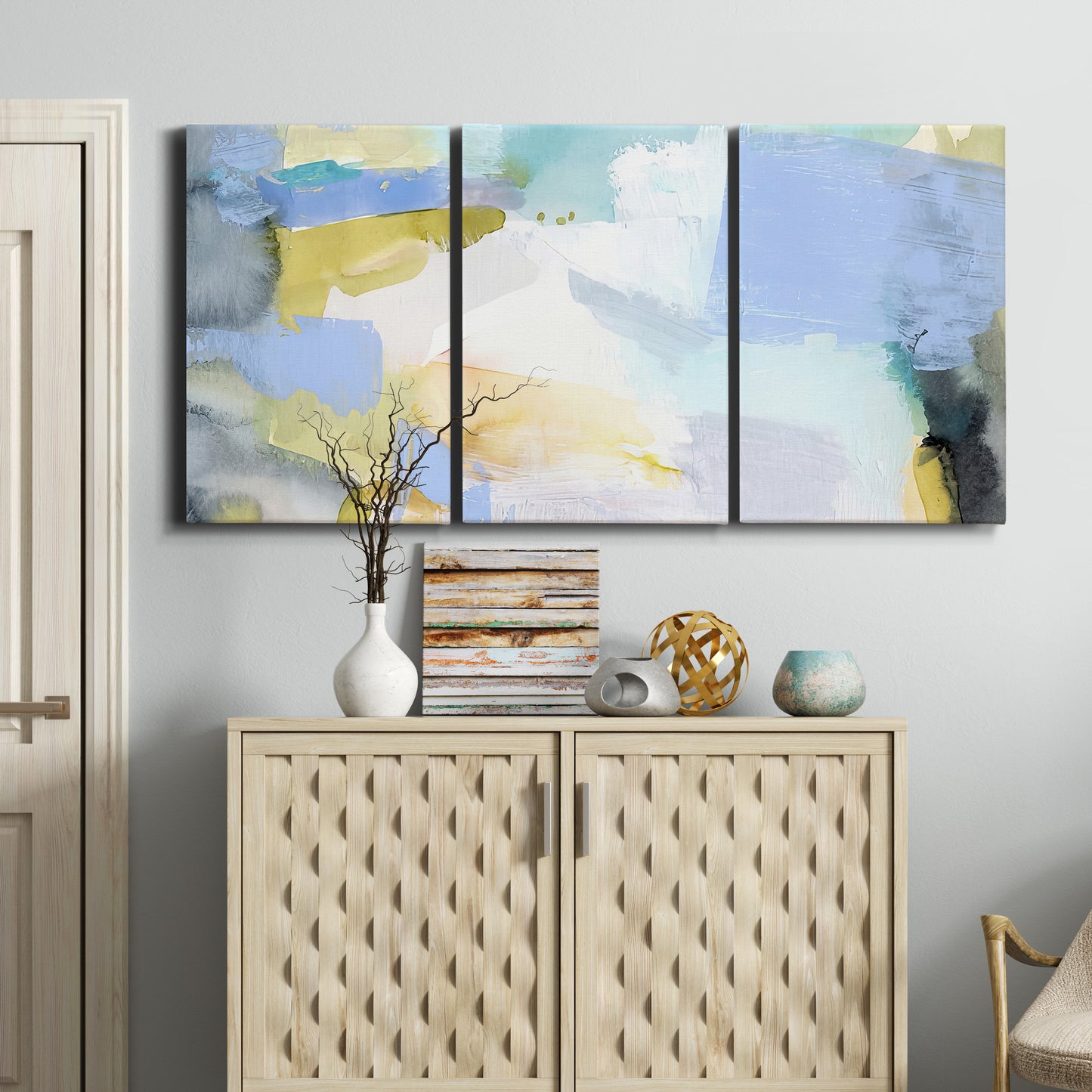 Three-panel canvas wall art featuring soft abstract spring watercolor tones, displayed above a cabinet in an entryway.