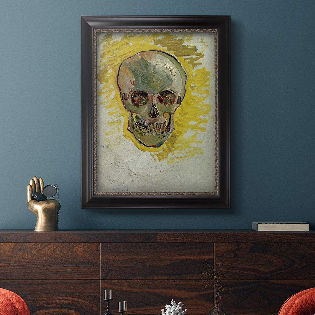 Expressive skull study painting by Vincent van Gogh in an ornate black frame with gilded inner detail displayed in a dark-toned interior setting.