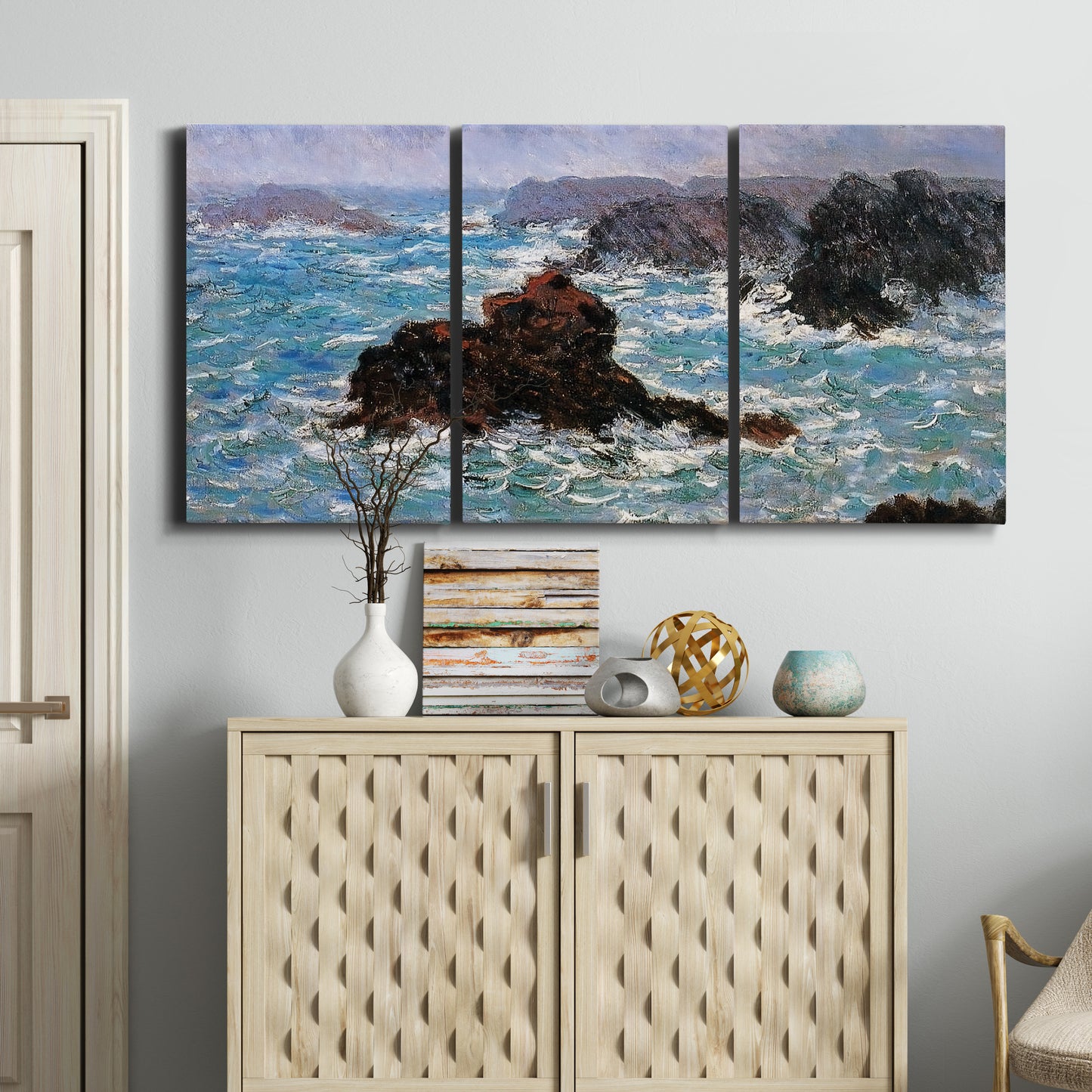 Three-panel canvas wall art featuring storm waves battering rocky coast, displayed above a cabinet in an entryway.