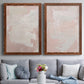 Set of two maple barnwood framed canvas prints depicting paired minimalist color-field abstracts with cloudy rose washes, broad pale strokes, and subtle texture above a sofa in a contemporary living room.