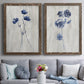 Set of two walnut barnwood framed canvas prints depicting paired rustic monochrome botanical paintings with indigo blossoms, thin stems, and softly distressed gray backgrounds above a sofa in a contemporary living room.