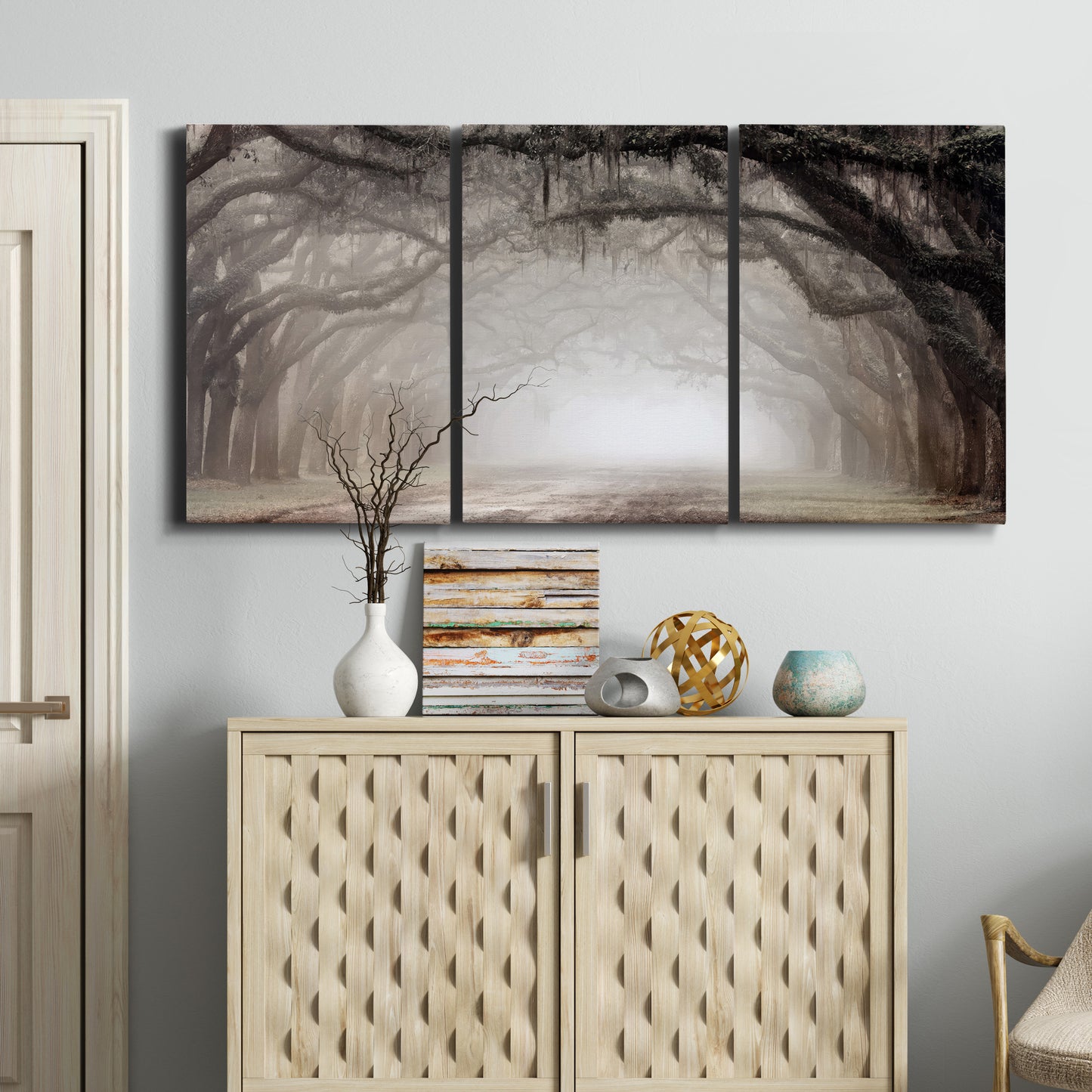Three-panel canvas wall art featuring tree lined plantation road, displayed above a cabinet in an entryway.