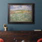 Impressionist countryside landscape near Auvers by Vincent van Gogh in an ornate black frame with gilded inner detail displayed in a dark-toned interior setting.
