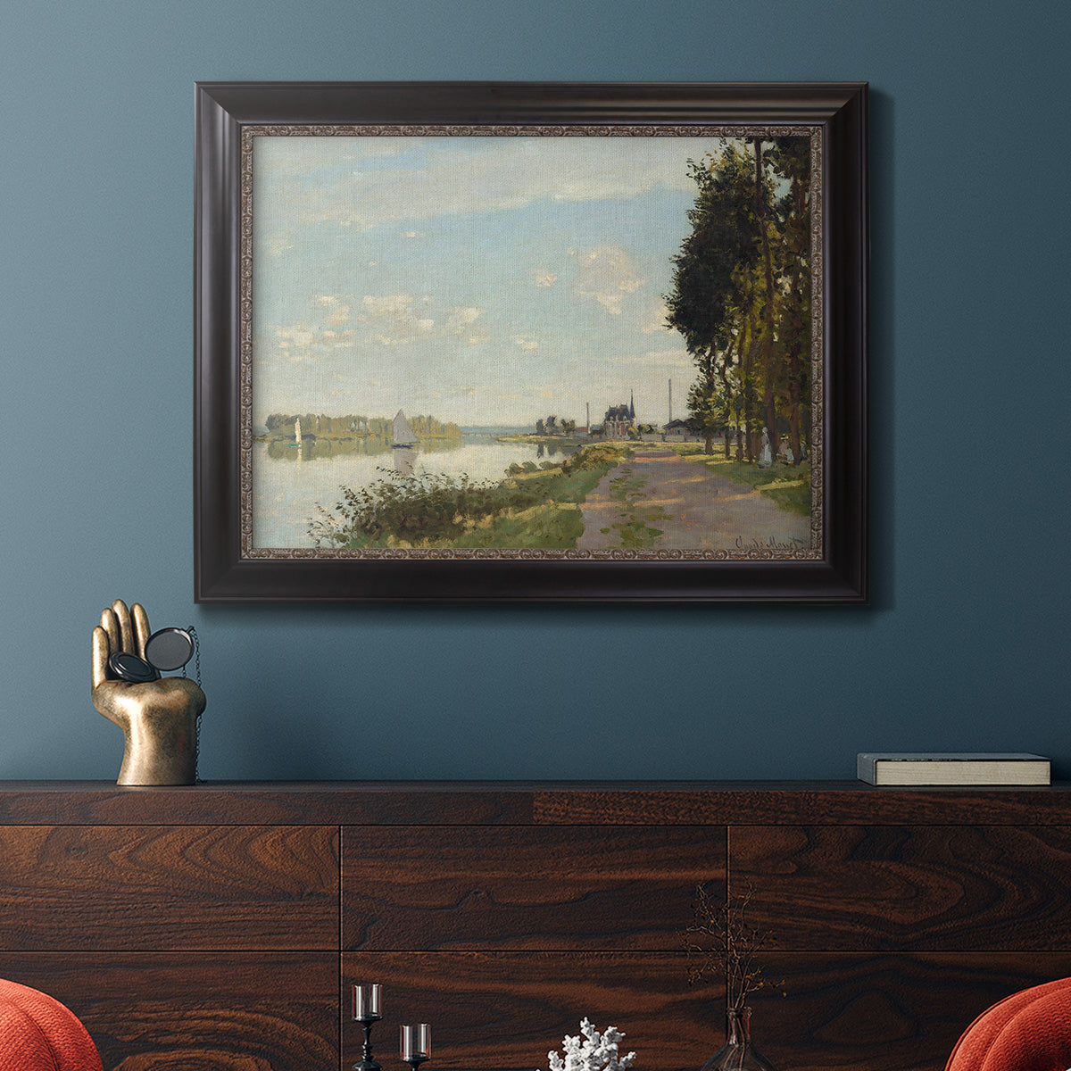 Impressionist river scene with red boats by Claude Monet in an ornate black frame with gilded inner detail displayed in a dark-toned interior setting.