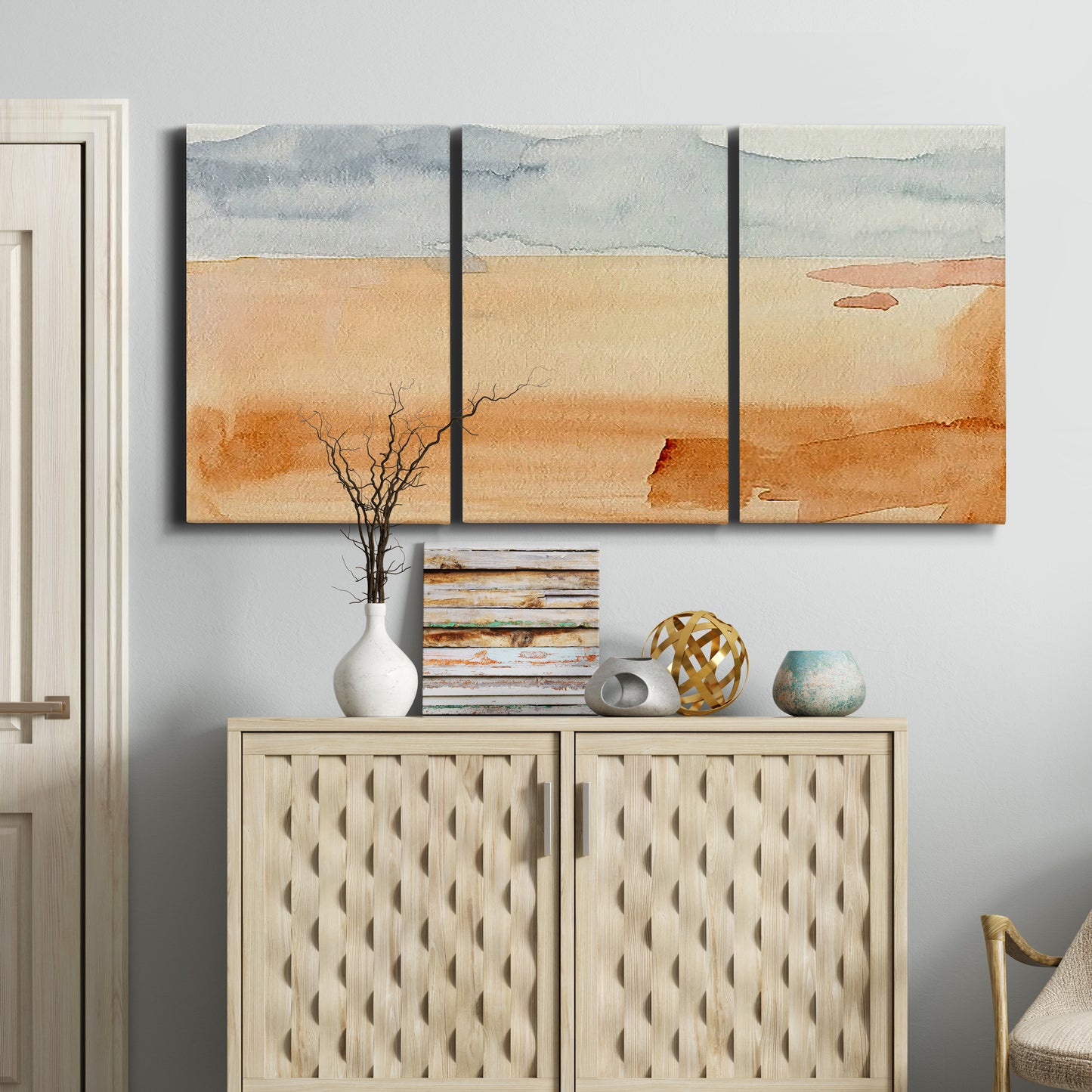 Three-panel canvas wall art featuring minimal horizon with soft blue tones, displayed above a cabinet in an entryway.
