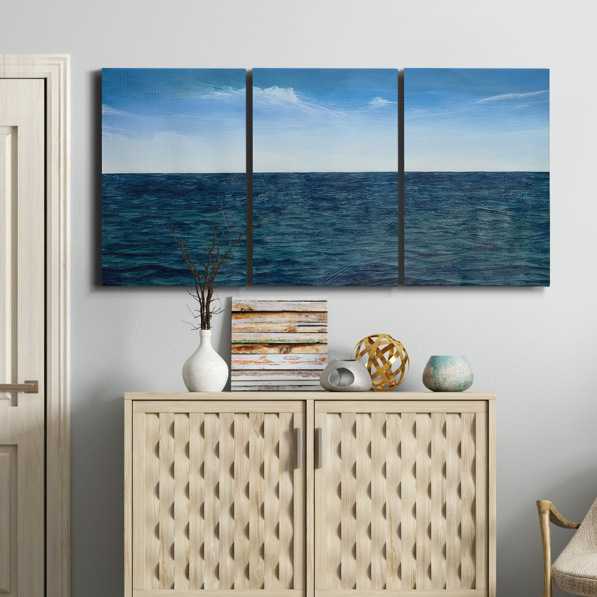 Three-panel canvas wall art featuring open water landscape with wide horizon, displayed above a cabinet in an entryway.