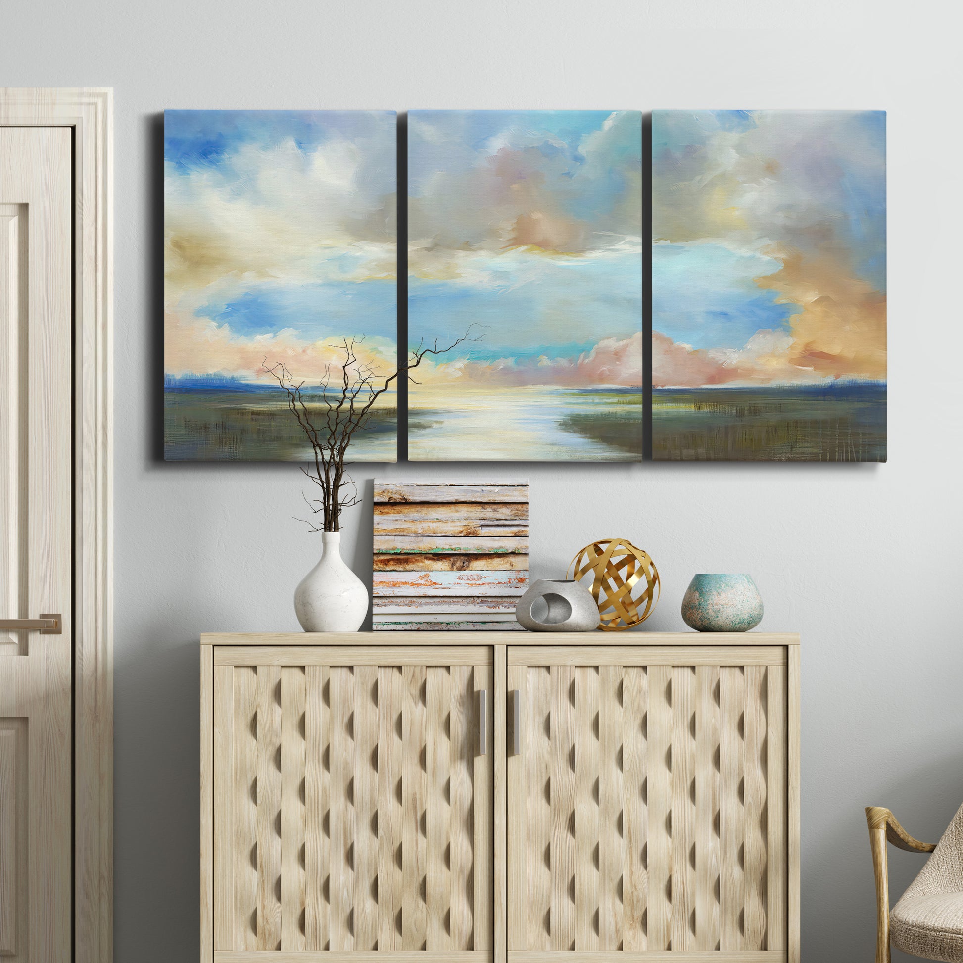 Three-panel canvas wall art featuring dawn light breaking over water, displayed above a cabinet in an entryway.