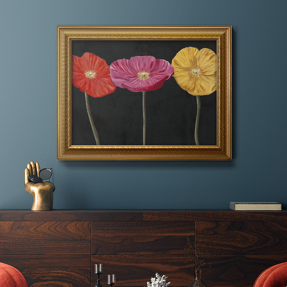 Contemporary poppy flower artwork in an ornate traditional gold frame displayed in a dark-toned interior setting.
