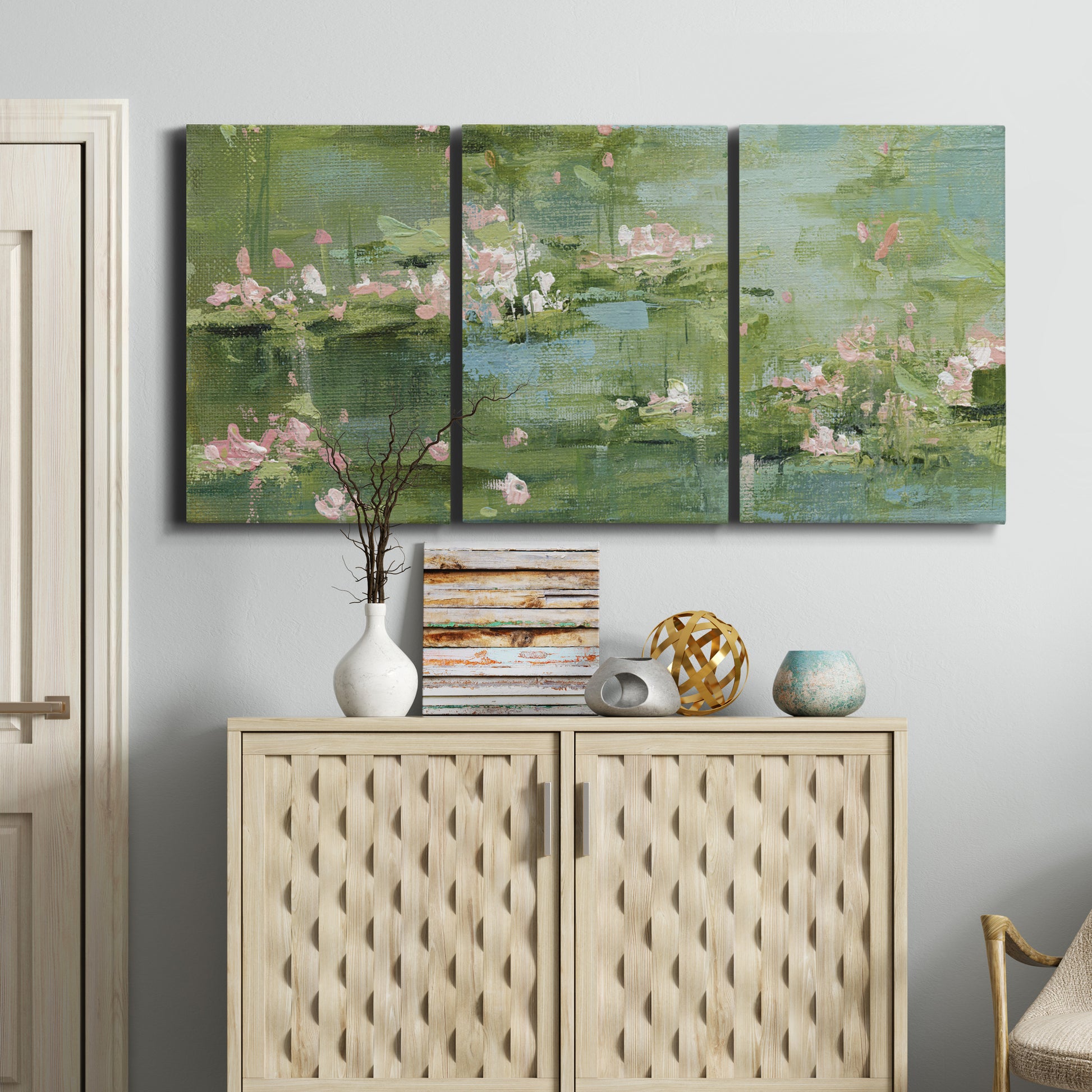 Three-panel canvas wall art featuring soft green water lilies, displayed above a cabinet in an entryway.