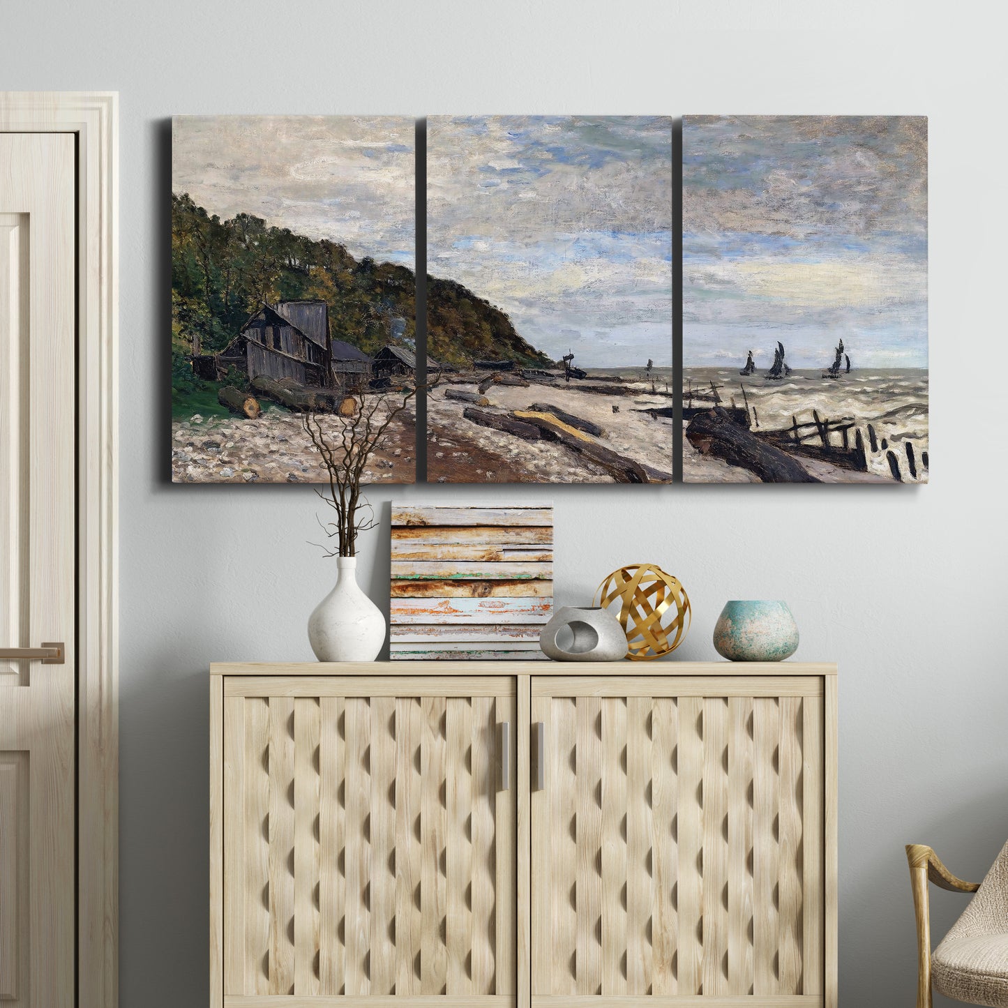 Three-panel canvas wall art featuring open sea along rocky shore, displayed above a cabinet in an entryway.