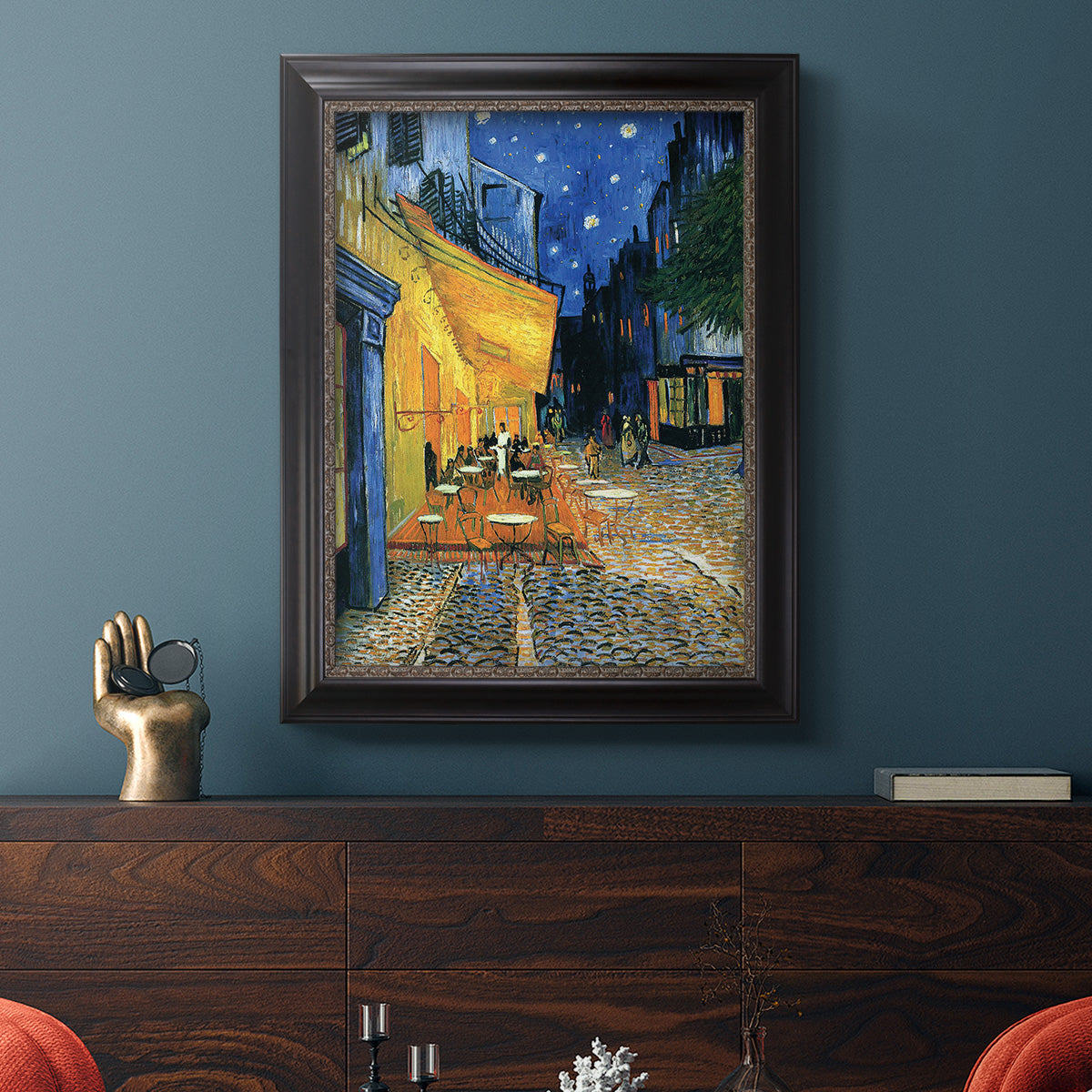 Impressionist night café street scene by Vincent van Gogh in an ornate black frame with gilded inner detail displayed in a dark-toned interior setting.