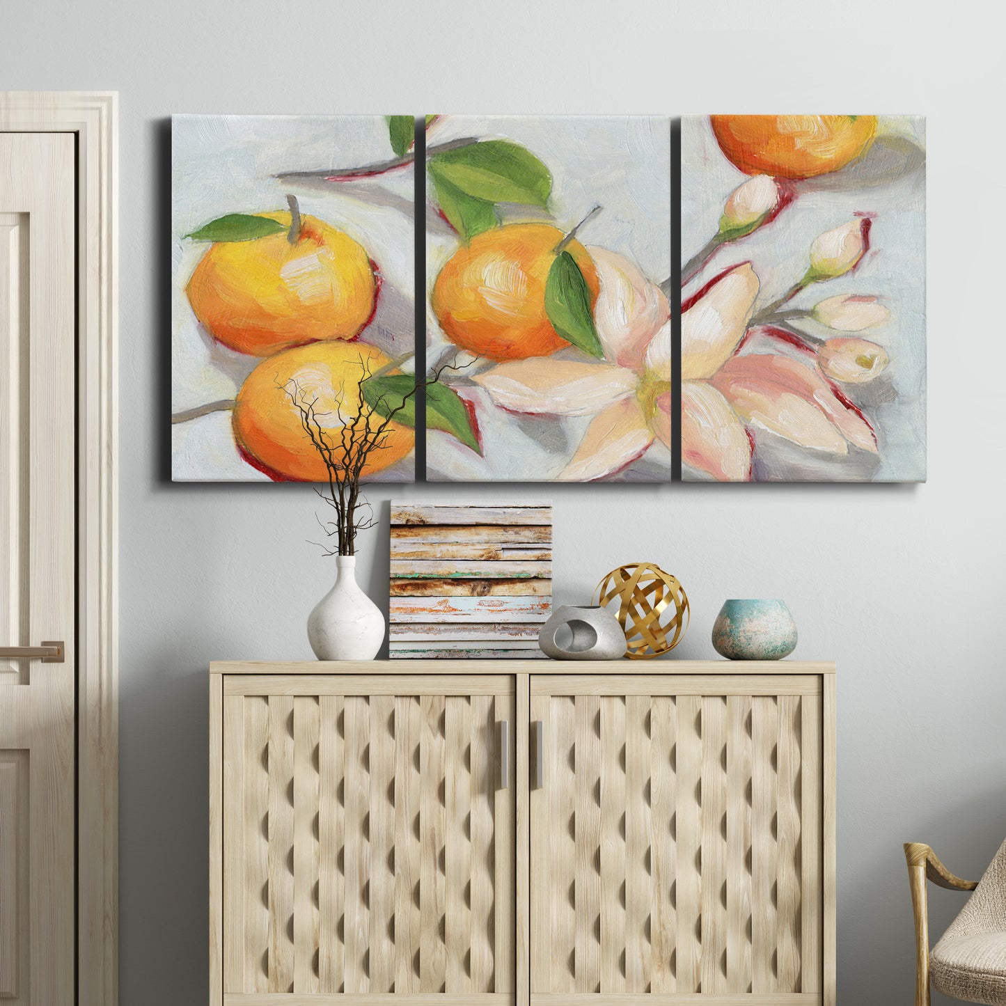 Three-panel canvas wall art featuring bright tangerine still life blossoms, displayed above a cabinet in an entryway.