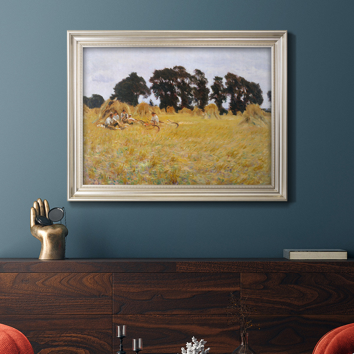Impressionist rural harvest scene by John Singer Sargent in an ornate champagne frame displayed in a dark-toned interior setting.