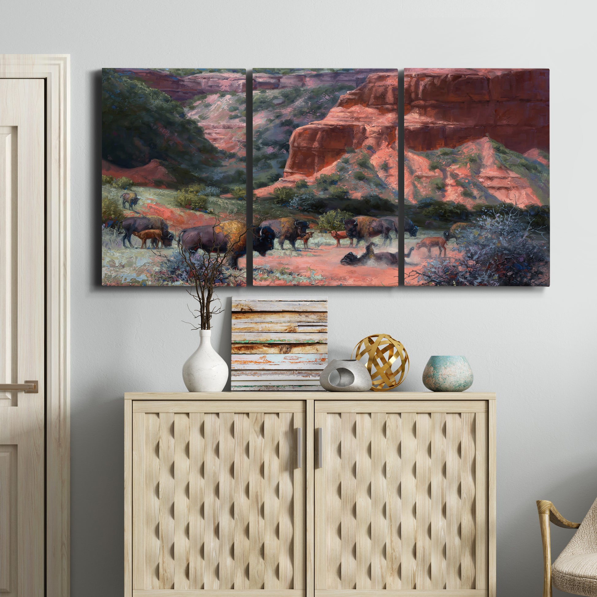 Three-panel canvas wall art featuring rugged canyon landscape with wildlife, displayed above a cabinet in an entryway.