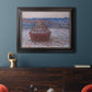 Impressionist single haystack landscape by Claude Monet in an ornate black frame with gilded inner detail displayed in a dark-toned interior setting.