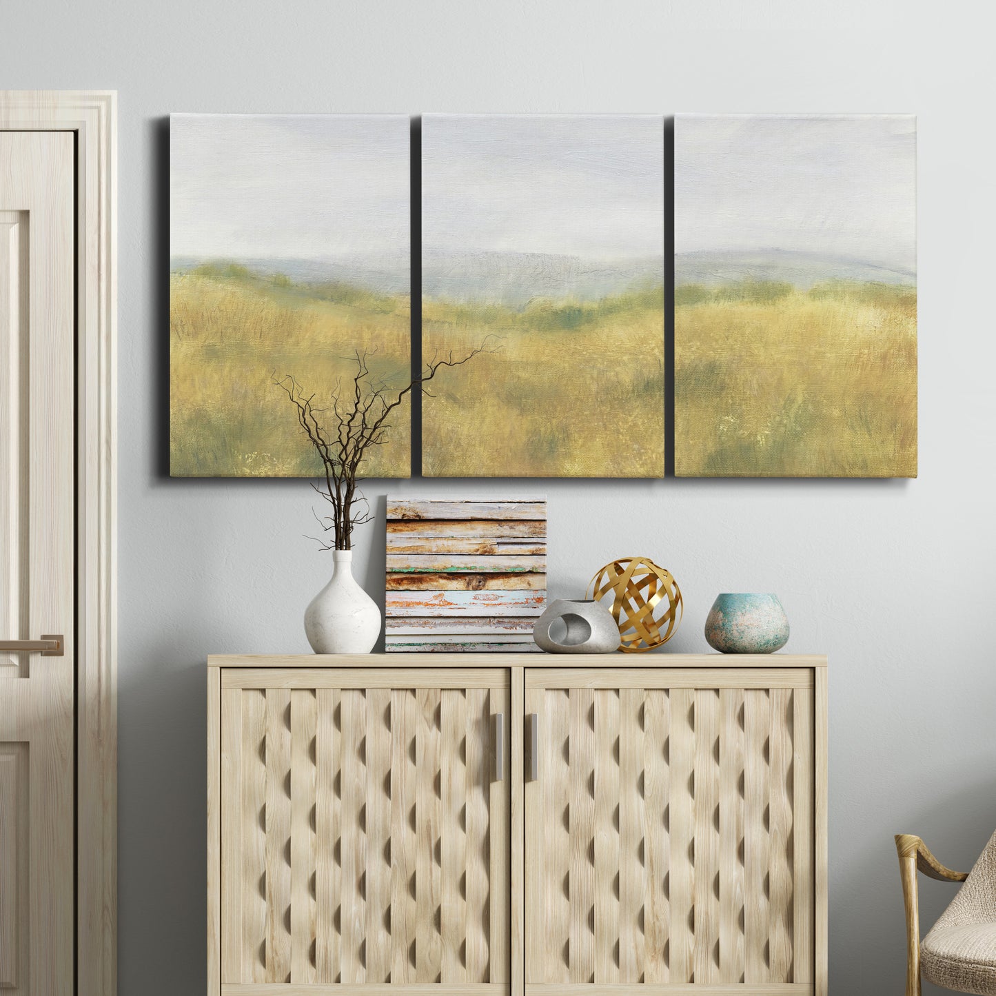 Three-panel canvas wall art featuring pastoral wheat field landscape, displayed above a cabinet in an entryway.