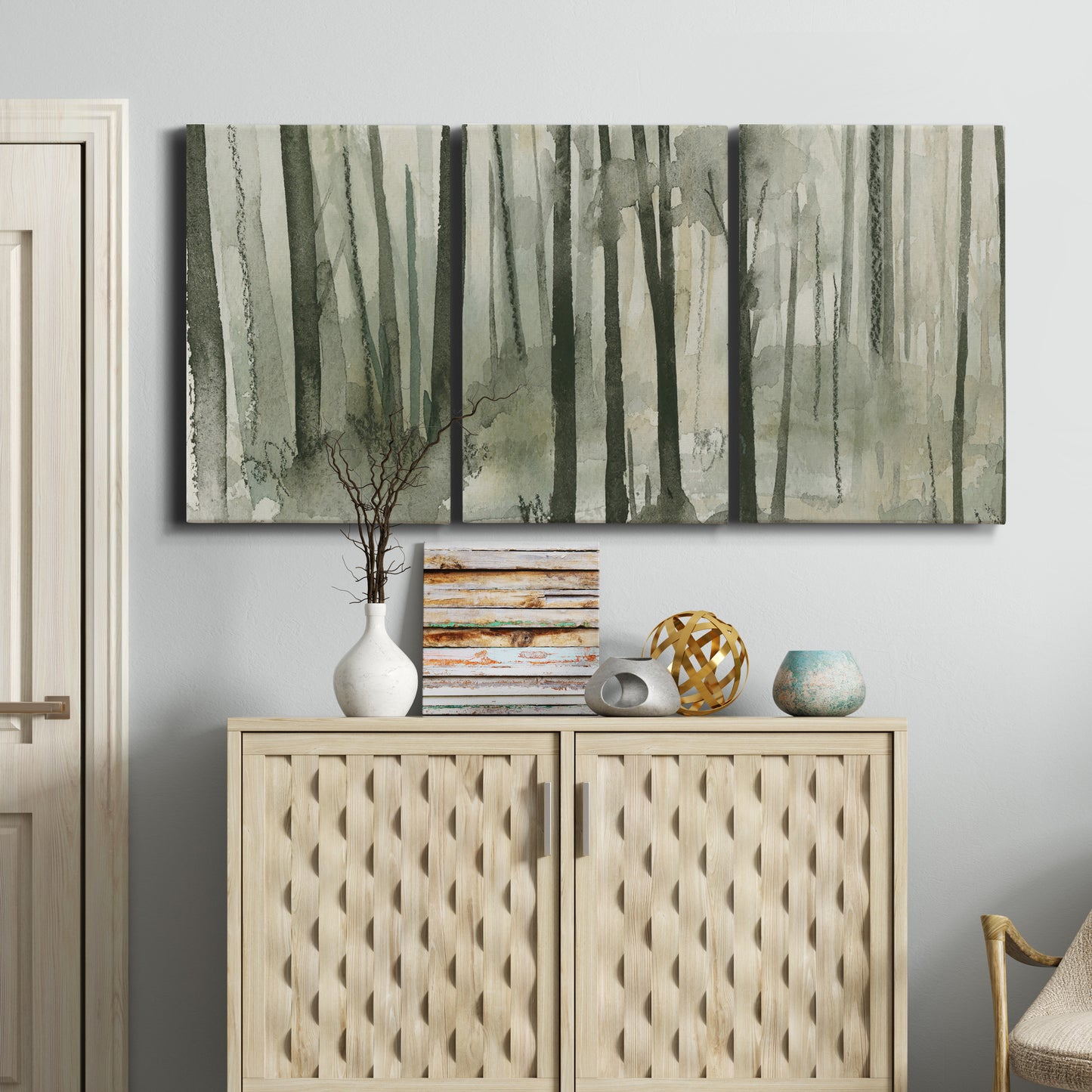 Three-panel canvas wall art featuring wooded forest path watercolor, displayed above a cabinet in an entryway.