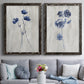 Set of two black barnwood framed canvas prints depicting paired rustic monochrome botanical paintings with indigo blossoms, thin stems, and softly distressed gray backgrounds above a sofa in a contemporary living room.