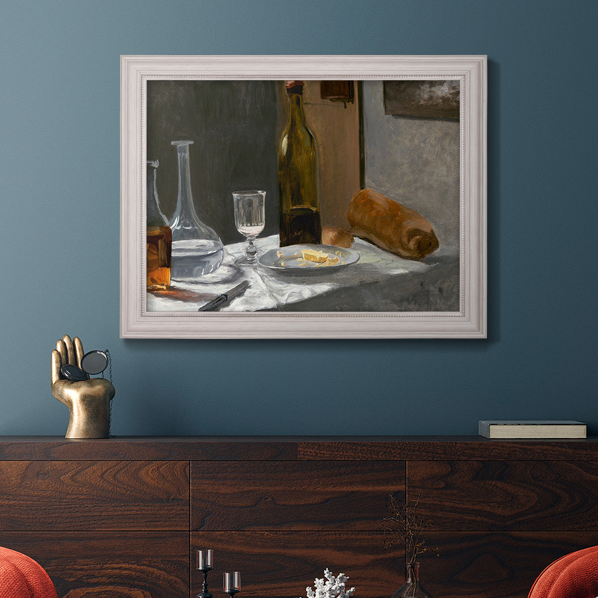 Impressionist still life with wine and bread by Claude Monet in an ornate weathered white frame displayed in a dark-toned interior setting.
