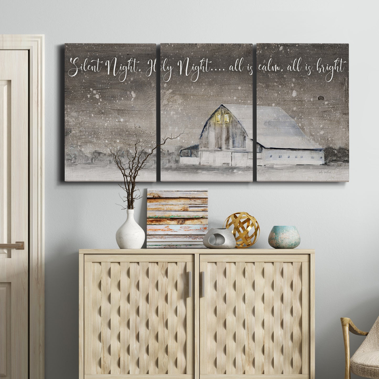 Three-panel canvas wall art featuring rustic winter holiday text art, displayed above a cabinet in an entryway.