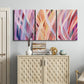 Three-panel canvas wall art featuring layered modern abstract color ribbons, displayed above a cabinet in an entryway.